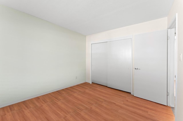 unfurnished bedroom featuring light wood-type flooring and a closet