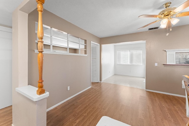 unfurnished living room featuring ceiling fan, hardwood / wood-style floors, and a textured ceiling