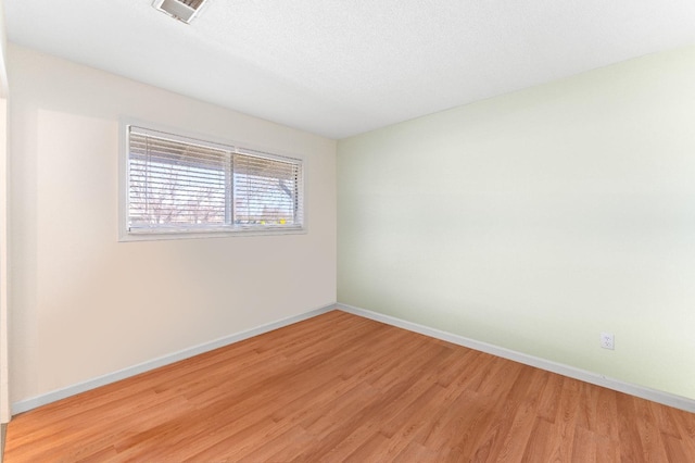 spare room featuring light hardwood / wood-style flooring and a textured ceiling