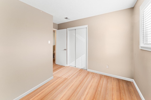 unfurnished bedroom featuring light hardwood / wood-style floors and a closet