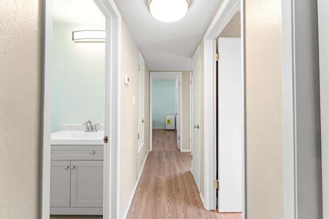 hallway with sink and light wood-type flooring