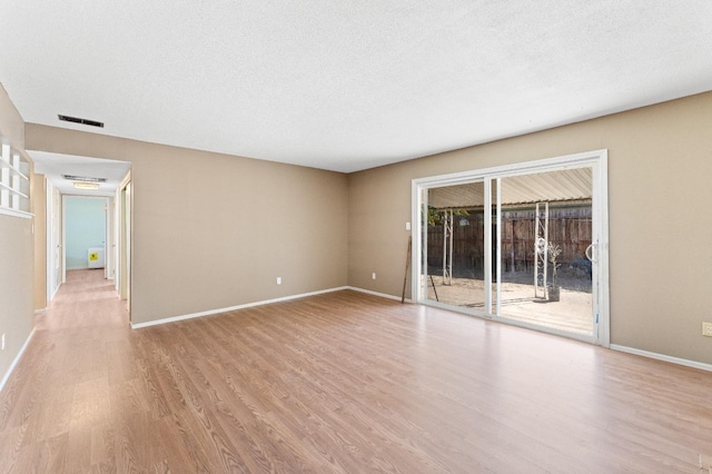 spare room with light hardwood / wood-style floors and a textured ceiling