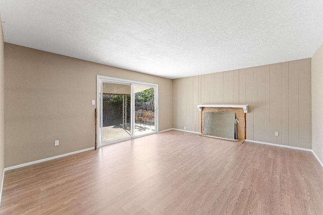 unfurnished living room with a fireplace, light hardwood / wood-style flooring, and a textured ceiling