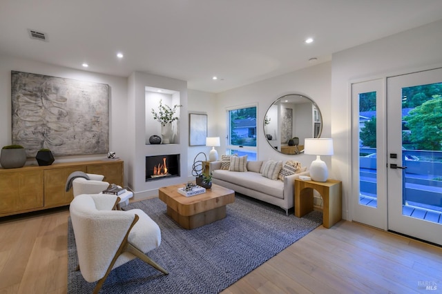 living area featuring light wood finished floors, recessed lighting, visible vents, and a lit fireplace