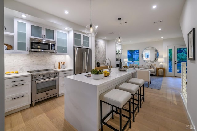 kitchen with visible vents, high end appliances, recessed lighting, and white cabinetry