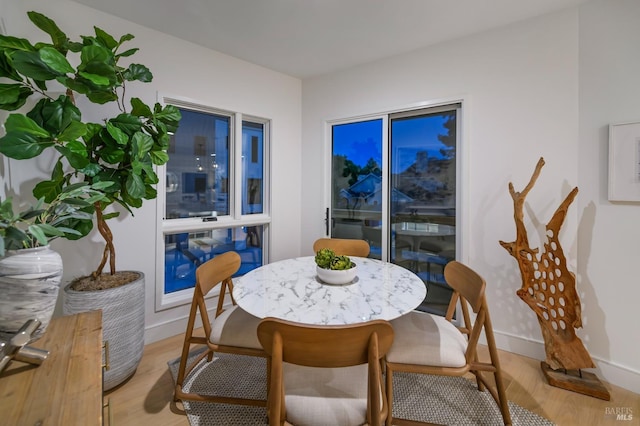 dining area featuring light wood finished floors and baseboards