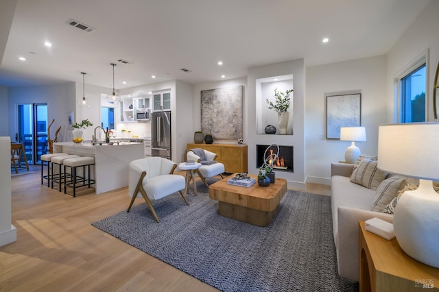 living room with recessed lighting, visible vents, and light wood-type flooring