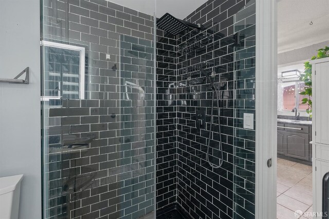 bathroom featuring tile patterned floors, a tile shower, and toilet
