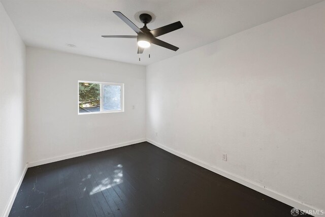 unfurnished room with dark wood-type flooring, ceiling fan, and baseboards