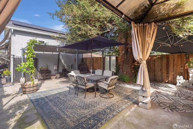 view of patio with fence, outdoor dining space, and a gazebo
