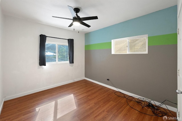 empty room with baseboards, wood finished floors, and a ceiling fan