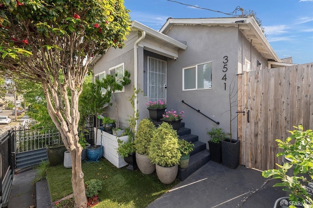 exterior space featuring stucco siding and fence