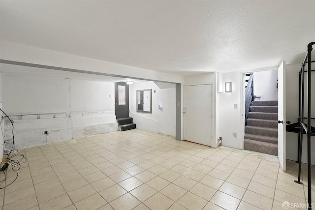 interior space with light tile patterned flooring, stairway, and a textured ceiling