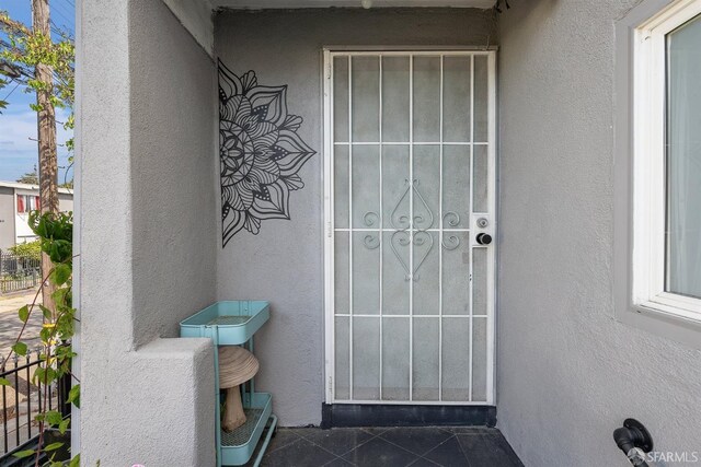 doorway to property with stucco siding and fence