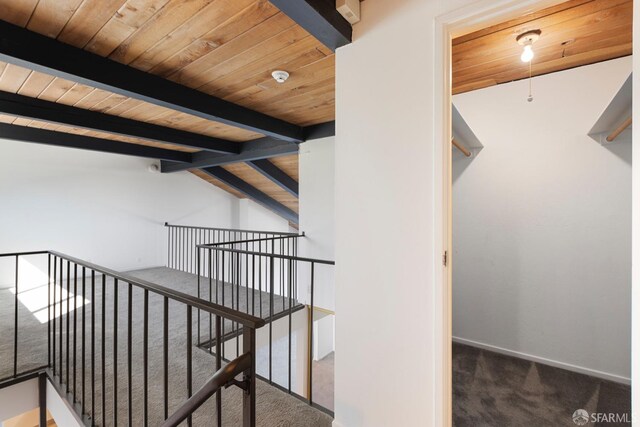 hall with baseboards, wooden ceiling, vaulted ceiling with beams, carpet flooring, and an upstairs landing