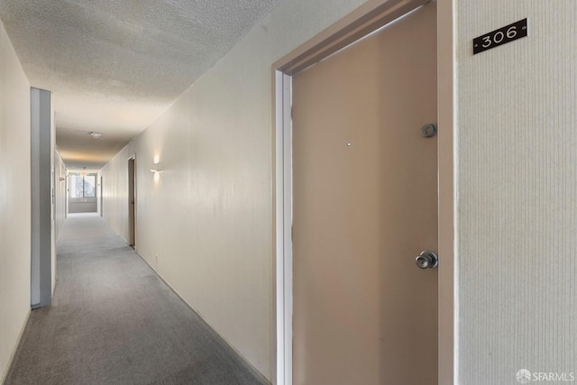 hall featuring carpet and a textured ceiling