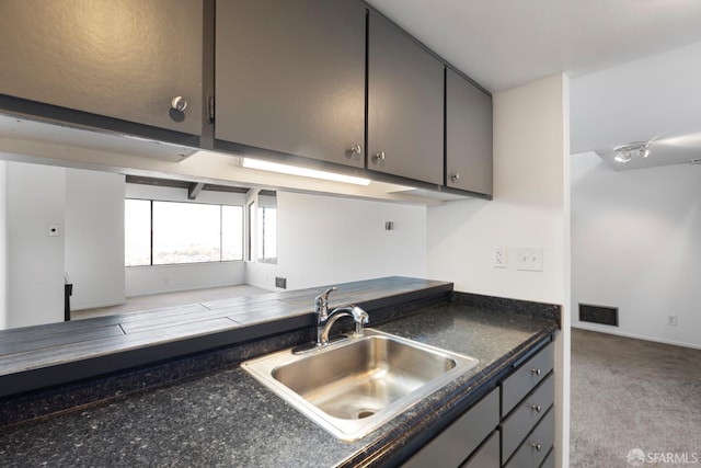 kitchen featuring carpet, dark countertops, visible vents, gray cabinetry, and a sink