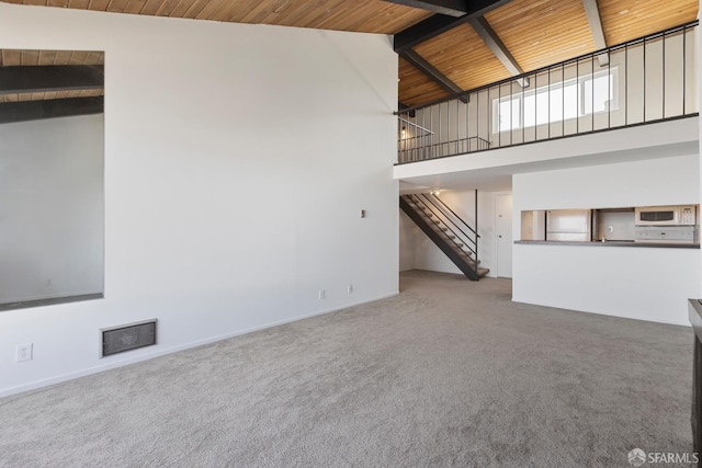 unfurnished living room featuring high vaulted ceiling, wooden ceiling, stairway, beamed ceiling, and carpet