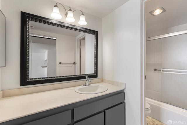 full bath featuring toilet, bath / shower combo with glass door, and vanity