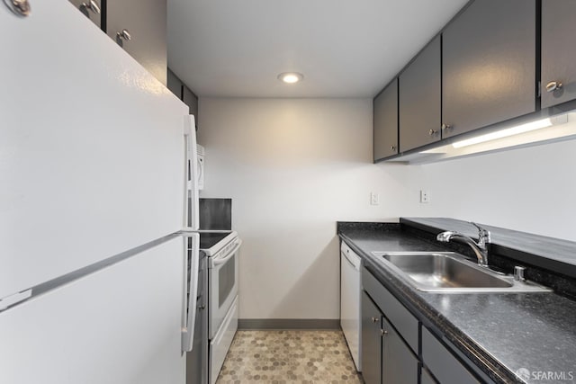 kitchen featuring dark countertops, white appliances, baseboards, and a sink