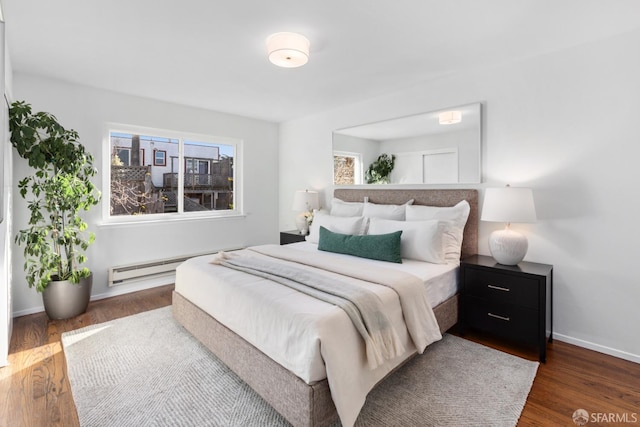 bedroom with dark wood-type flooring and a baseboard heating unit