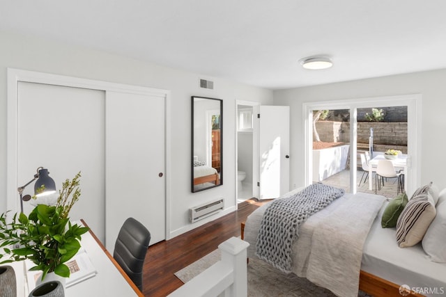 bedroom featuring dark hardwood / wood-style flooring, connected bathroom, access to outside, and a wall mounted air conditioner