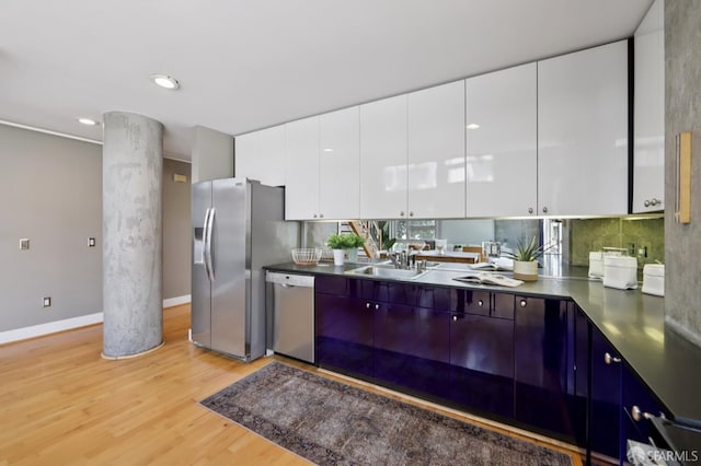 311 Oak St Unit 301, Oakland, CA 94607 - kitchen with stainless steel appliances, a sink, light wood-style flooring, white cabinets, and baseboards