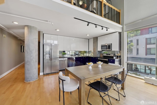 311 Oak St Unit 301, Oakland, CA 94607 - dining space with light wood-style floors, rail lighting, and baseboards