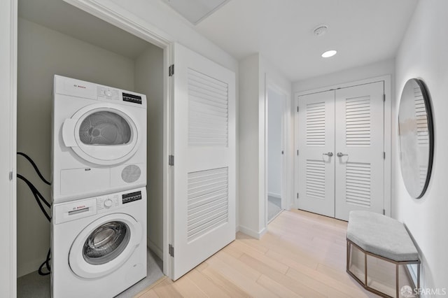 laundry room with light wood-type flooring and stacked washer / dryer