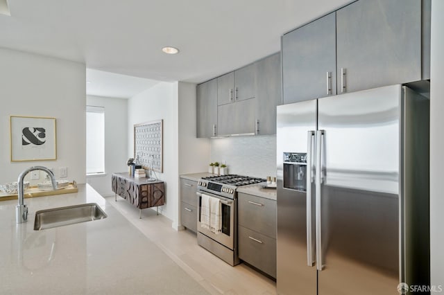 kitchen with decorative backsplash, stainless steel appliances, sink, light hardwood / wood-style flooring, and gray cabinets