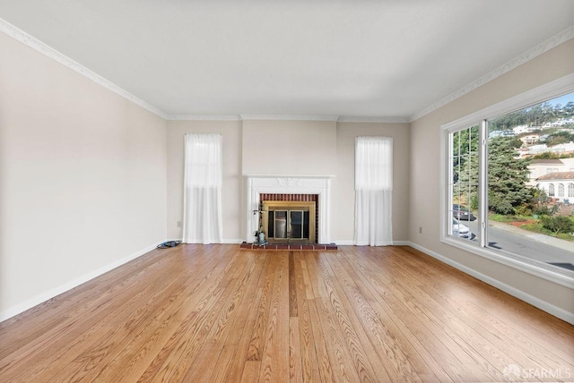 unfurnished living room featuring light wood-type flooring, a brick fireplace, and crown molding