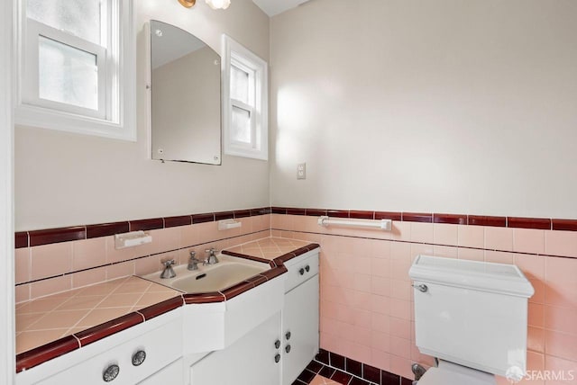 bathroom with vanity, toilet, and tile walls