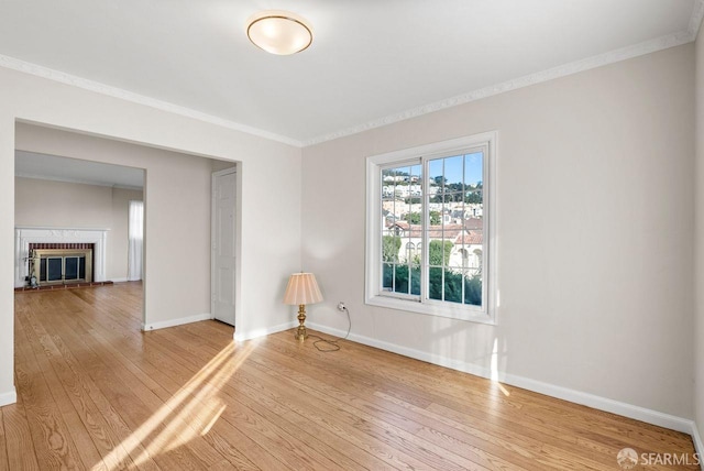 empty room with wood-type flooring, a fireplace, and ornamental molding