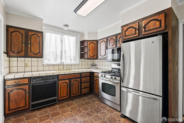 kitchen featuring black appliances, crown molding, sink, tasteful backsplash, and tile counters