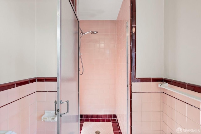 bathroom with a shower with door and tile walls