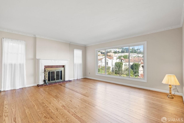 unfurnished living room with light wood-type flooring, a brick fireplace, and ornamental molding