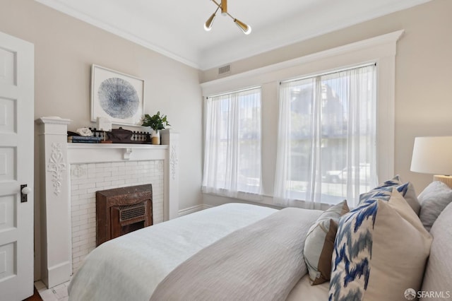 bedroom with ornamental molding, a fireplace, and visible vents