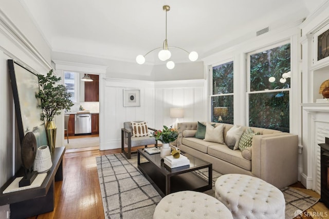 living area featuring a fireplace, wood finished floors, visible vents, and a decorative wall