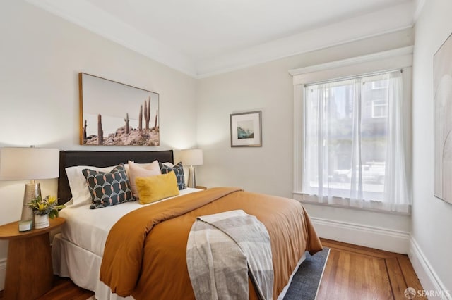 bedroom featuring multiple windows, baseboards, and wood finished floors