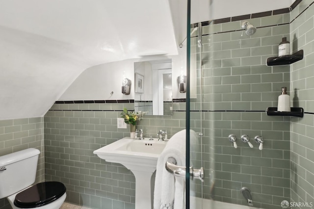 bathroom with toilet, vaulted ceiling, tile walls, and wainscoting