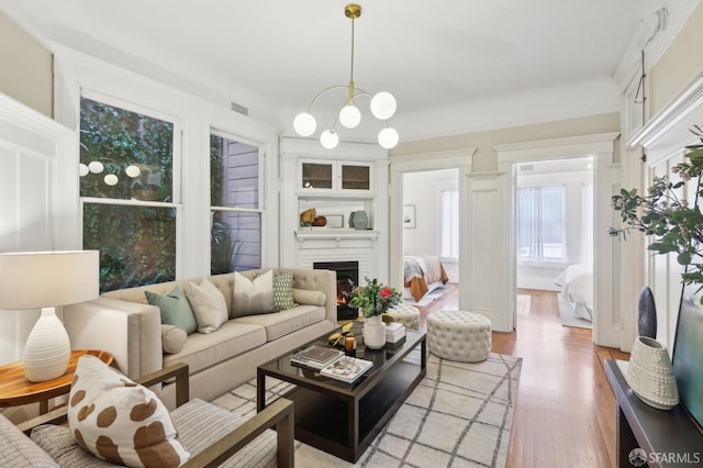 living room featuring light wood-style floors, a chandelier, and a large fireplace