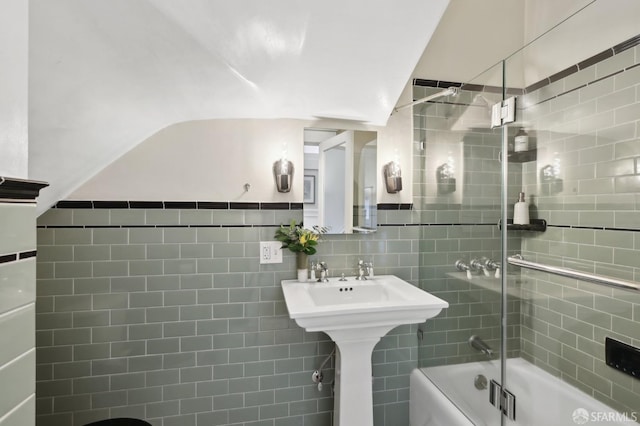 full bath with shower / bath combination with glass door, vaulted ceiling, and tile walls