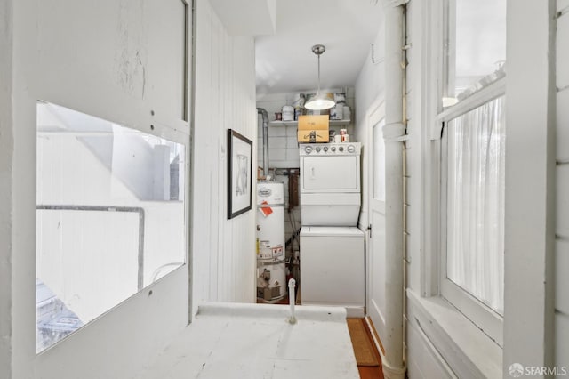 laundry area featuring water heater, laundry area, and stacked washing maching and dryer