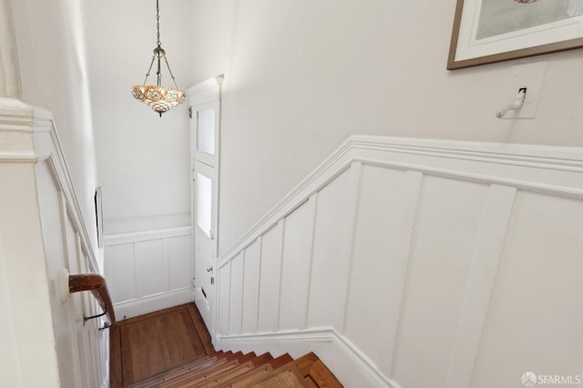 staircase with a wainscoted wall and a decorative wall