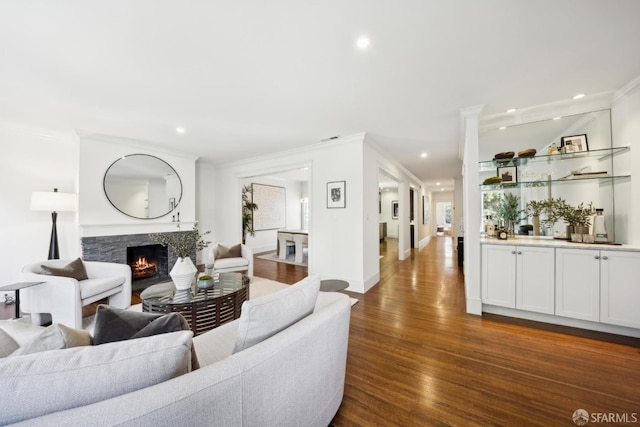 living area with dark wood-style floors, recessed lighting, a fireplace, and ornamental molding