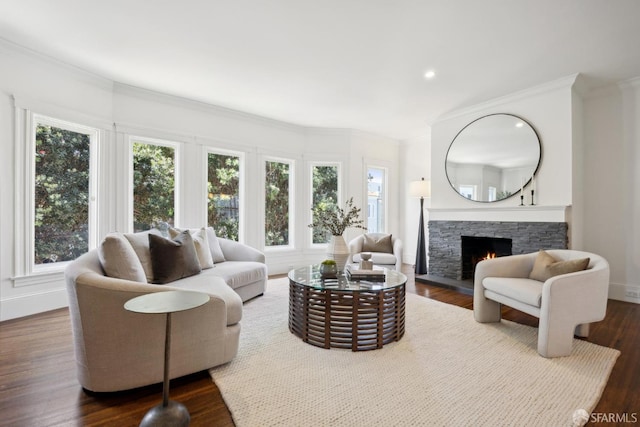 living area featuring baseboards, ornamental molding, dark wood-style flooring, a stone fireplace, and recessed lighting