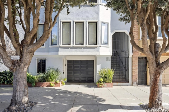 multi unit property with a garage, concrete driveway, and stucco siding