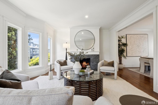 living area with recessed lighting, wood finished floors, baseboards, a lit fireplace, and ornamental molding