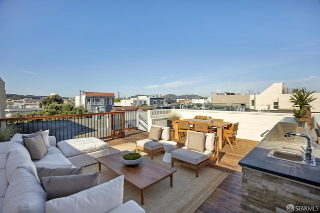 wooden terrace featuring an outdoor kitchen, an outdoor hangout area, a sink, and outdoor dining space