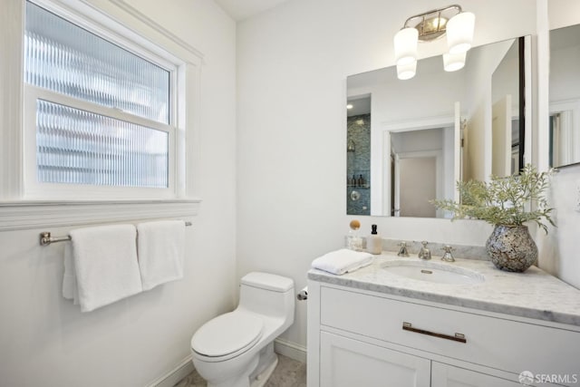 bathroom featuring a shower, vanity, toilet, and baseboards